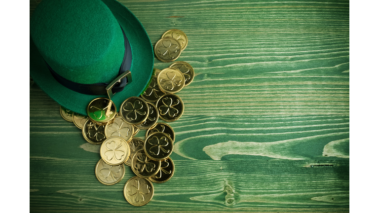 Happy St Patricks Day leprechaun hat with gold coins on vintage green wood background