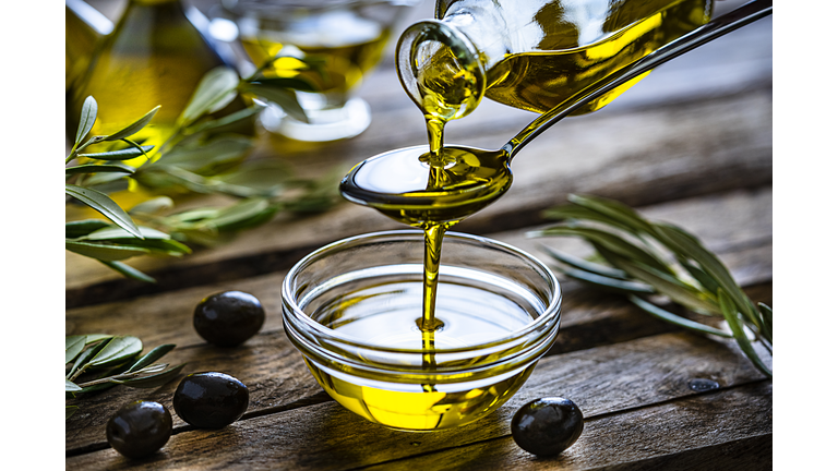 Pouring extra virgin olive oil in a glass bowl