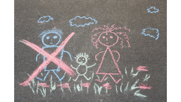 Children's drawing with chalk on the asphalt, family with no dad: crossed out dad, mom and baby. Family divorce topic.