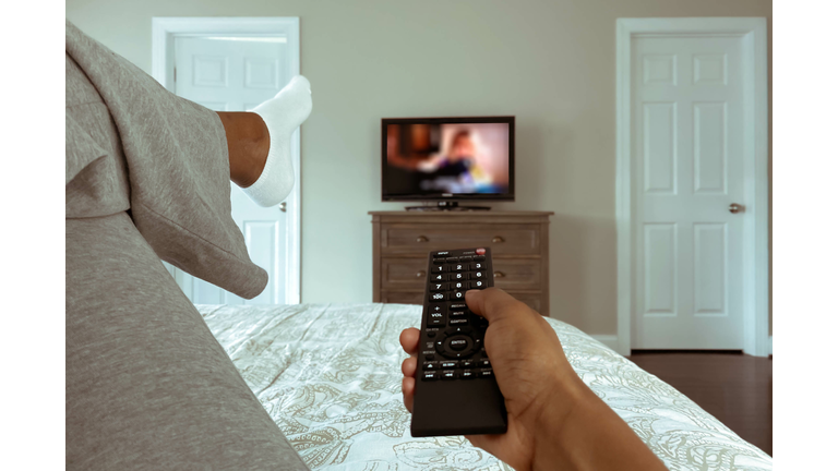 Woman Lounges in Bed Watching TV