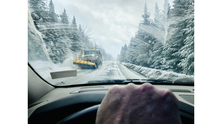 Man driving car during winter in Rangeley, Maine with snowplow coming down road