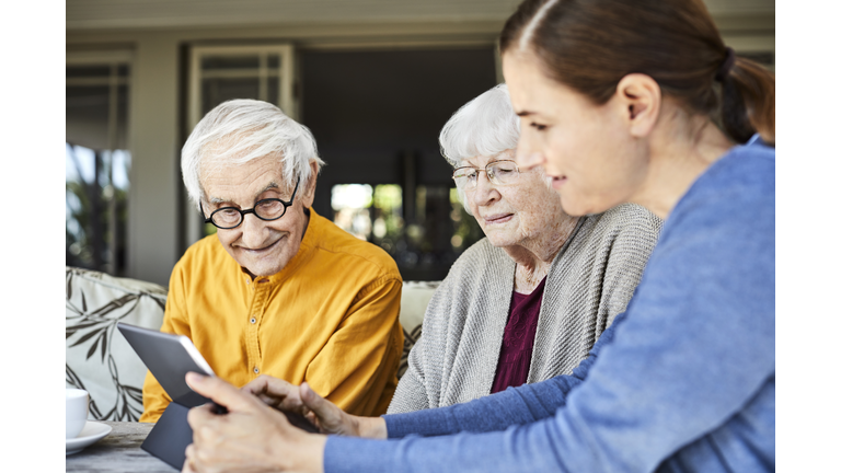 Nurse discussing with senior couple over tablet PC