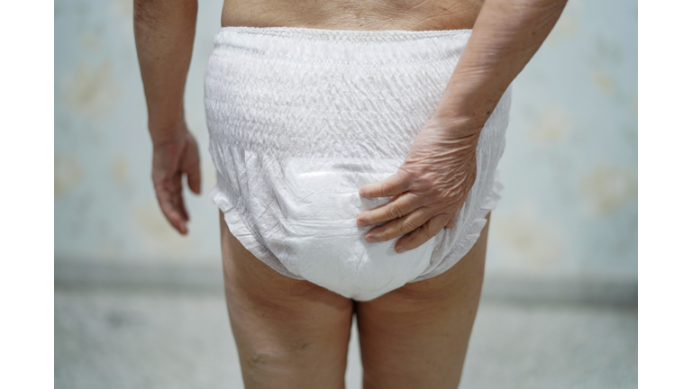 Midsection Of Woman Touching Diaper While Standing Against Wall