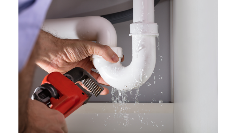 Plumber Fixing Sink Pipe With Adjustable Wrench