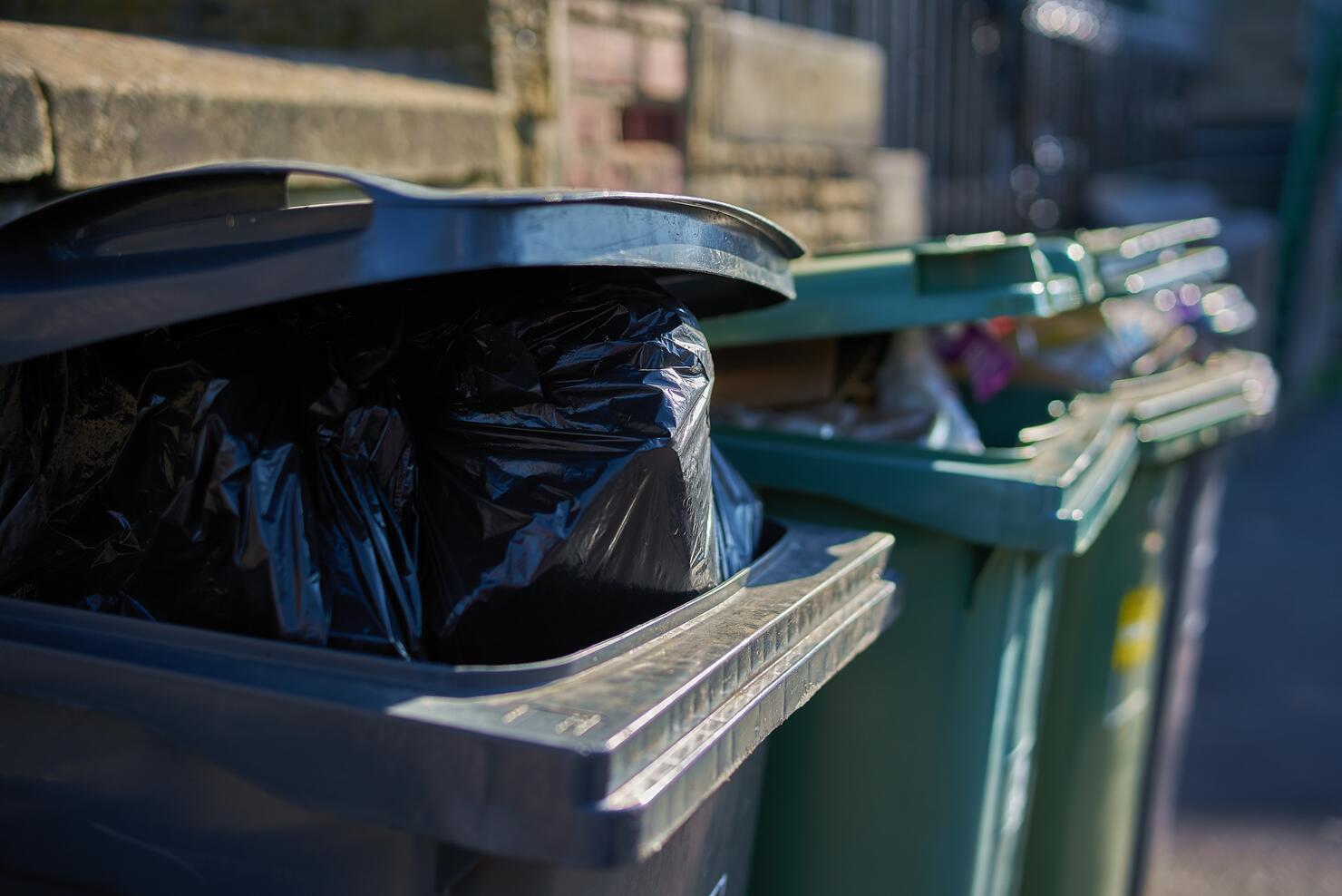 Overfull garbage cans wheelie bins close up