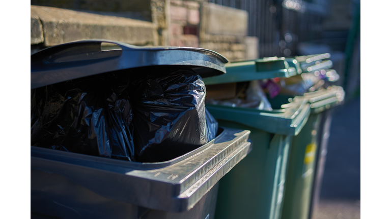 Overfull garbage cans wheelie bins close up