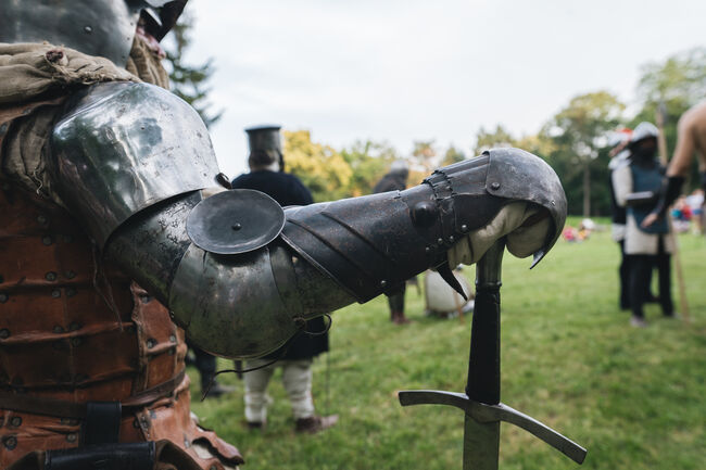 A knight in body armor with a long sword standing at a medieval festival