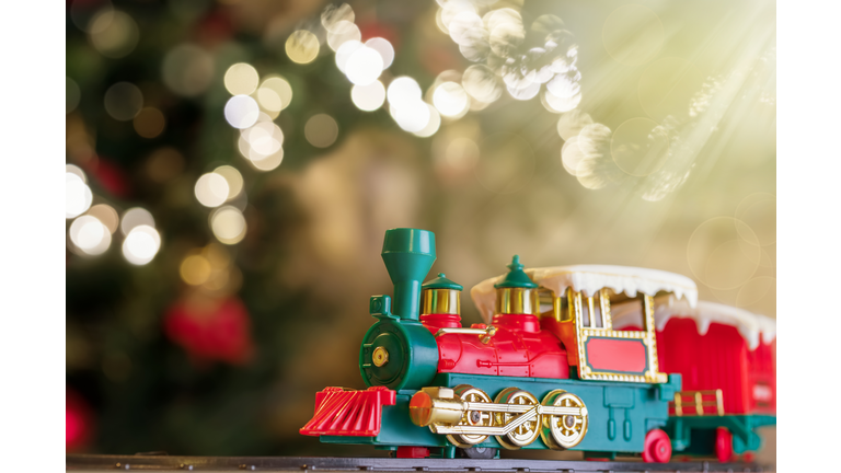 Toy train on Christmas tree background with defocused lights.