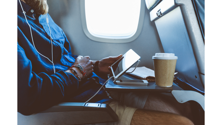 Man using digital tablet in airplane