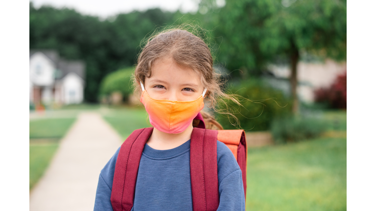 Caucasian little girl ready to go to school wearing a face mask