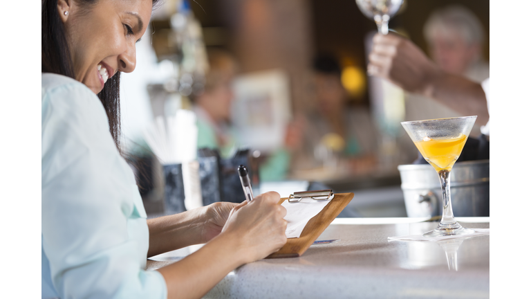 Woman signing receipt after paying bar tab in restaurant