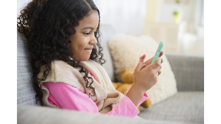 Mixed race girl texting with cell phone on sofa