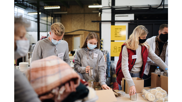 Group of volunteers in community charity donation center, food bank and coronavirus concept.