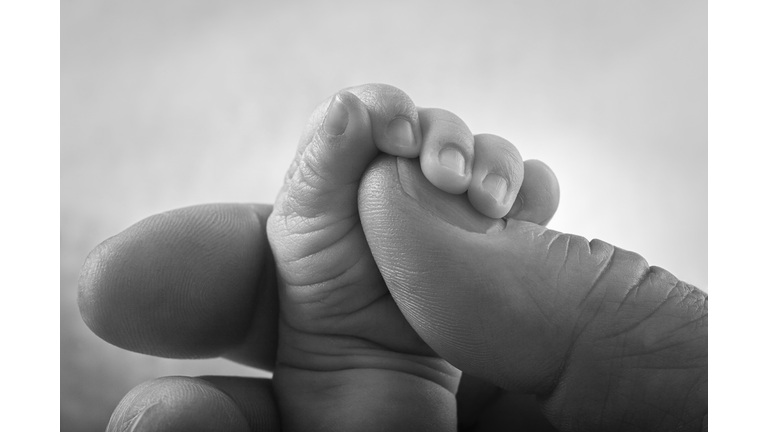 Newborn Baby Tiny Hand Holding Large Adult Man Fingers