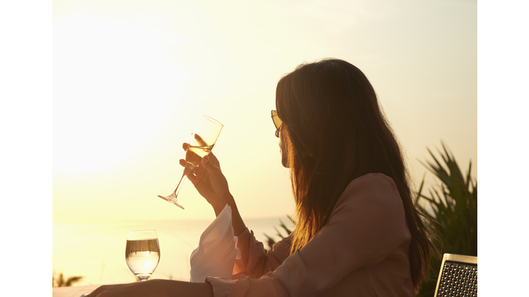 Hispanic woman drinking champagne at sunset dinner outdoors