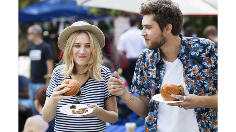 Couple eating burgers at food market