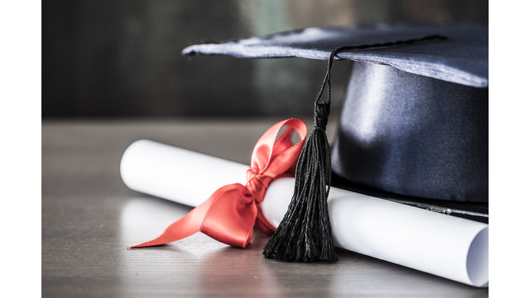 Graduation hat and diploma on table