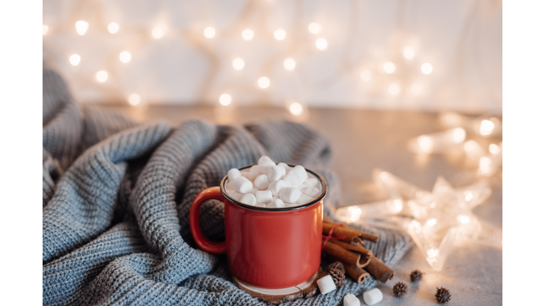 Christmas cocoa header with marshmallows, chocolate crumbs, and syrup. Large coffee cup with homemade hot chocolate. Winter drink photography on a dark background