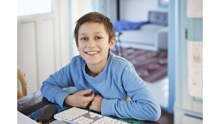 Portrait smiling boy using computer at table