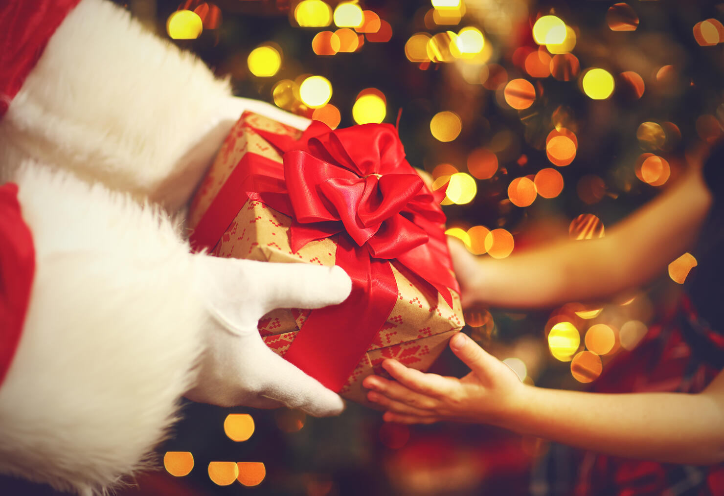 hands of Santa Claus give a child a Christmas gift