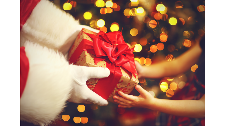 hands of Santa Claus give a child a Christmas gift