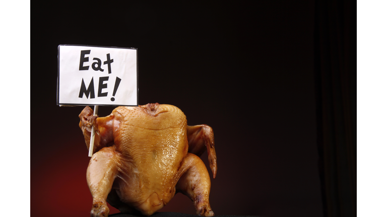A headless cooked turkey holding a sign that says eat me 