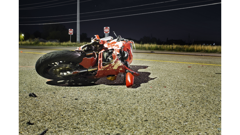 Close-up of wrecked red motorcycle on side of road