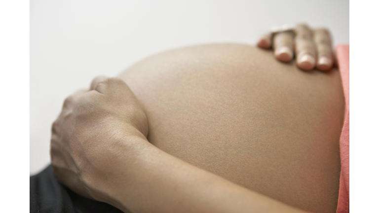 Close up of pregnant African woman's hands on bare belly
