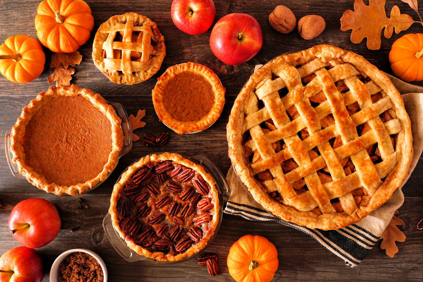 Variety of homemade autumn pies. Apple, pumpkin and pecan. Table scene over rustic wood.