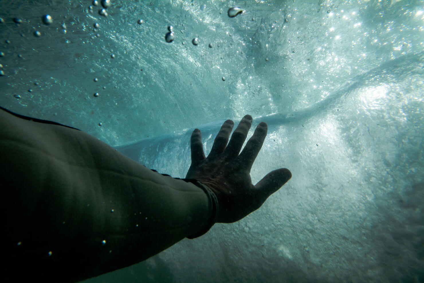 Hand reaching towards water surface