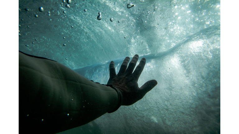 Hand reaching towards water surface