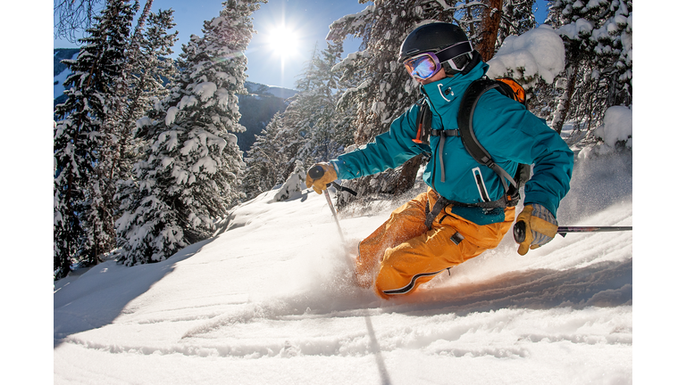 Skier skiing powder on a sunny day.