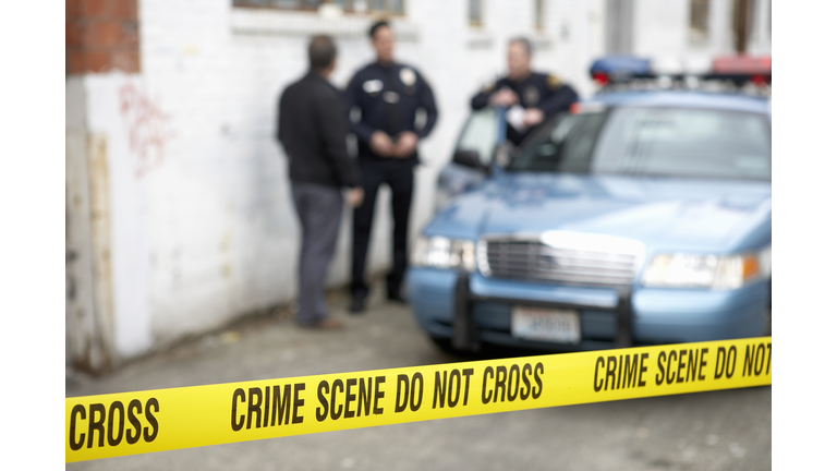 Male police officers standing behind Do Not Cross tape
