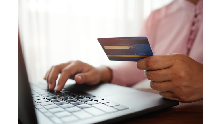 hands holding a credit card and using the laptop for online shopping and online payment via the internet. Technology concept.