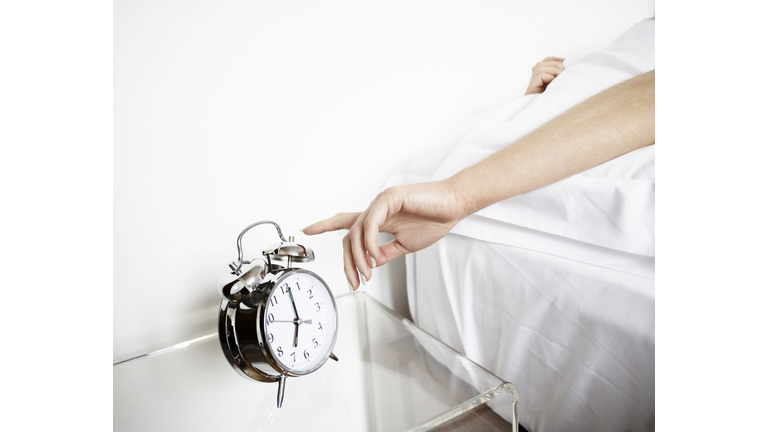 Woman reaching to turn off alarm clock