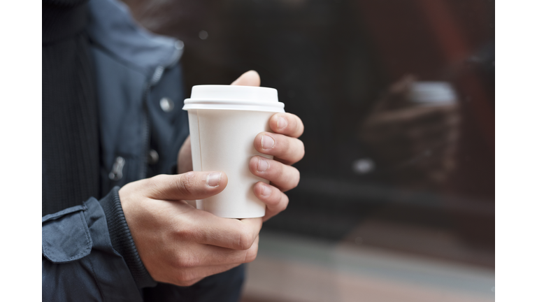 Young man holding a takeaway coffee outdoors