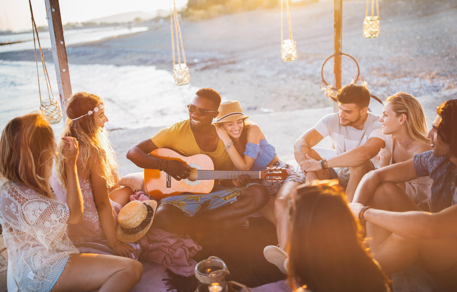 Young friends with guitar having fun at summer beach party