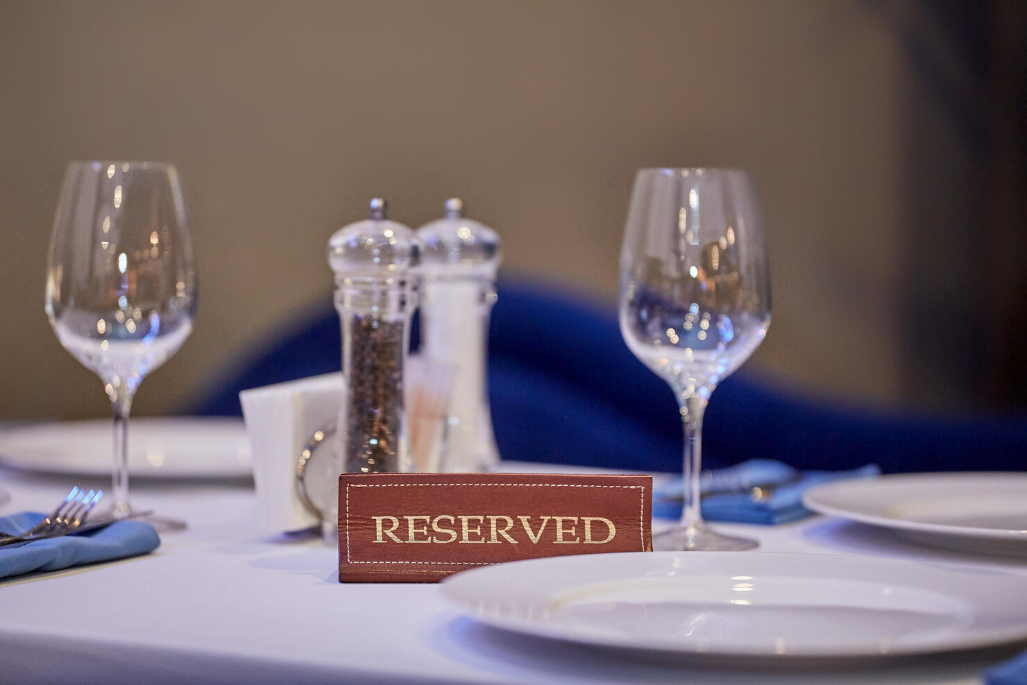 Restaurant reserved table sign with places setting and wine glasses ready for a party