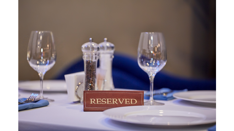 Restaurant reserved table sign with places setting and wine glasses ready for a party