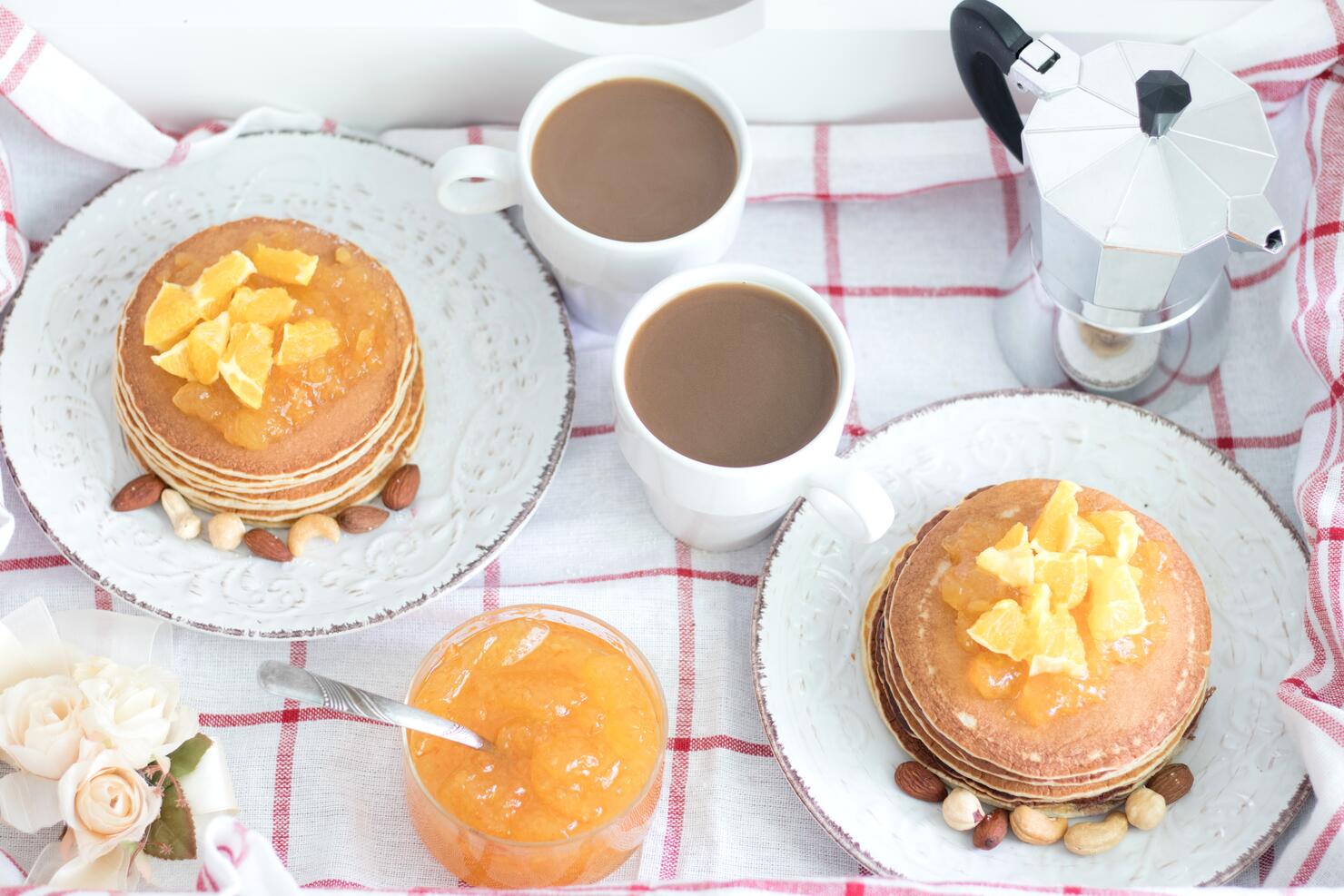 Breakfast for two. American pancakes with orange jam and nuts on vintage plates and 2 white coffee cups. Top view