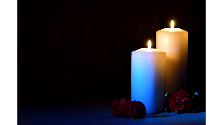 Day of memory and sorrow. Remember and mourn. Two white candles with flowers on black.