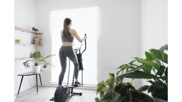 Woman performing workout on elliptical trainer at home