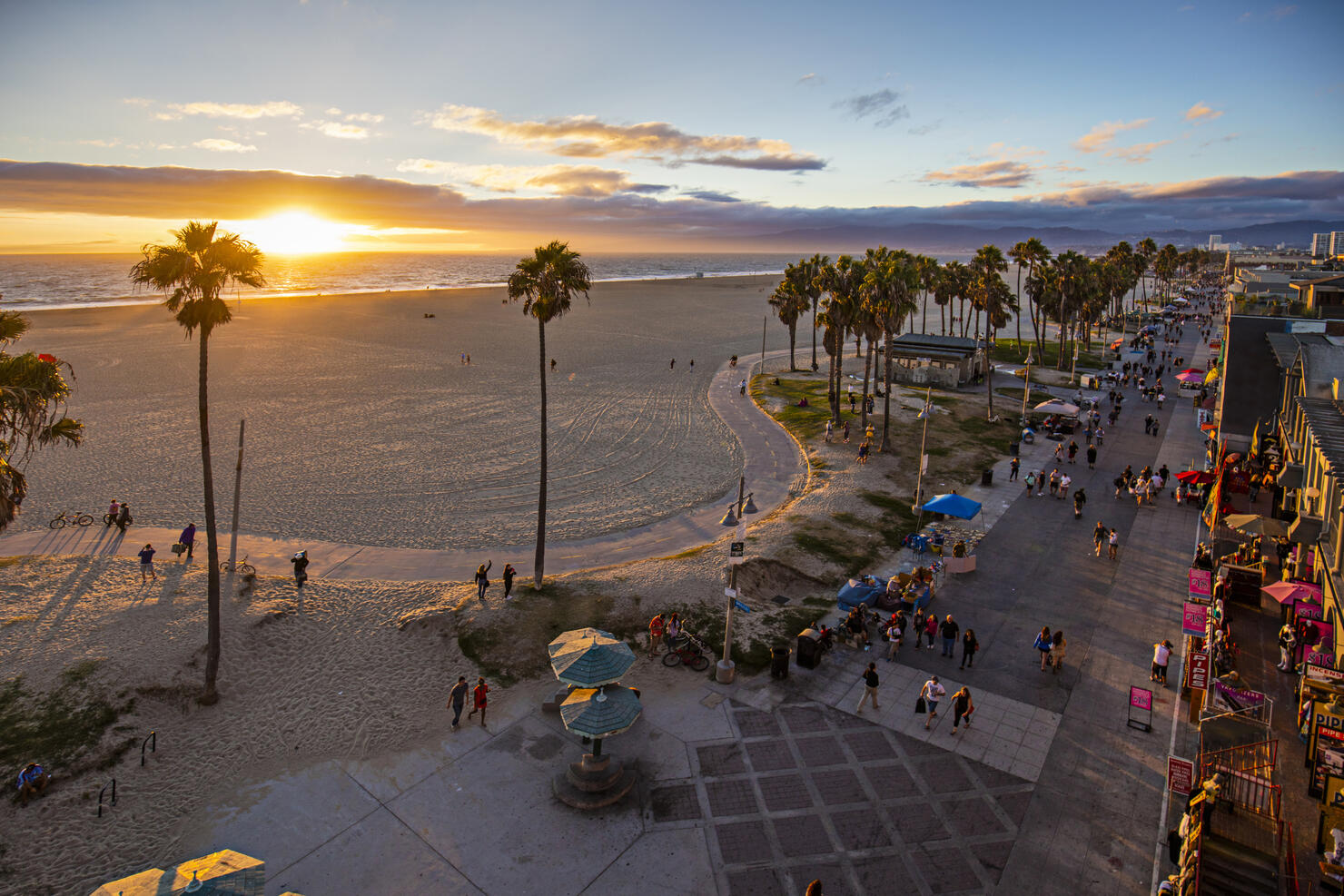 Tourists walking on footpath by beach during sunset