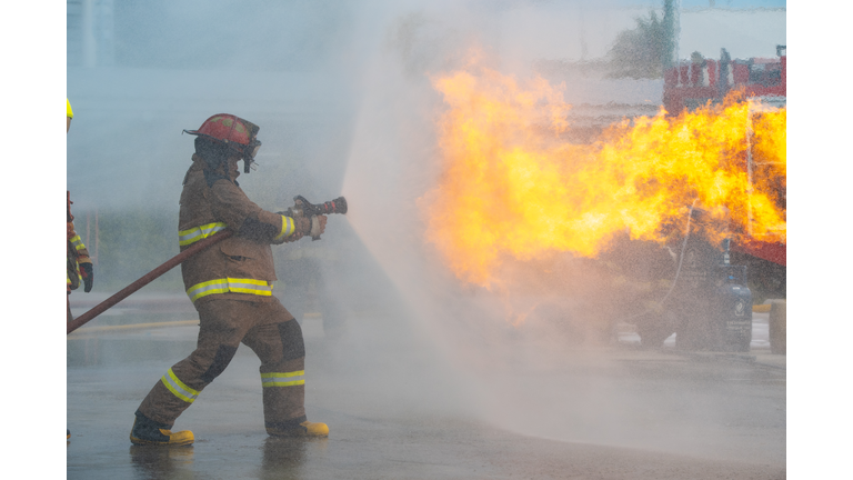 Firefighter spraying water at a house fire