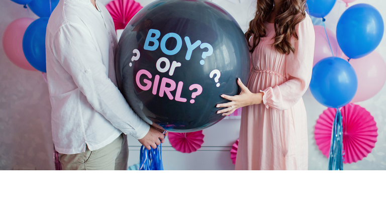 man and woman holding black balloon with "boy or girl?" on gender reveal party
