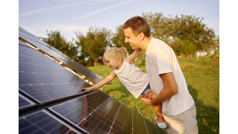 Father and daughter touching solar panel