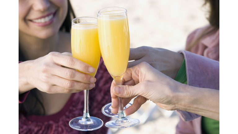 Multi-ethnic women toasting with mimosas