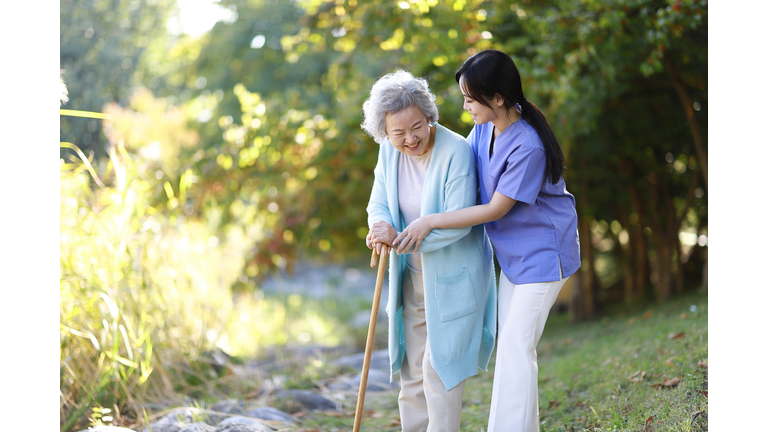 Nurse helping senior woman with cane