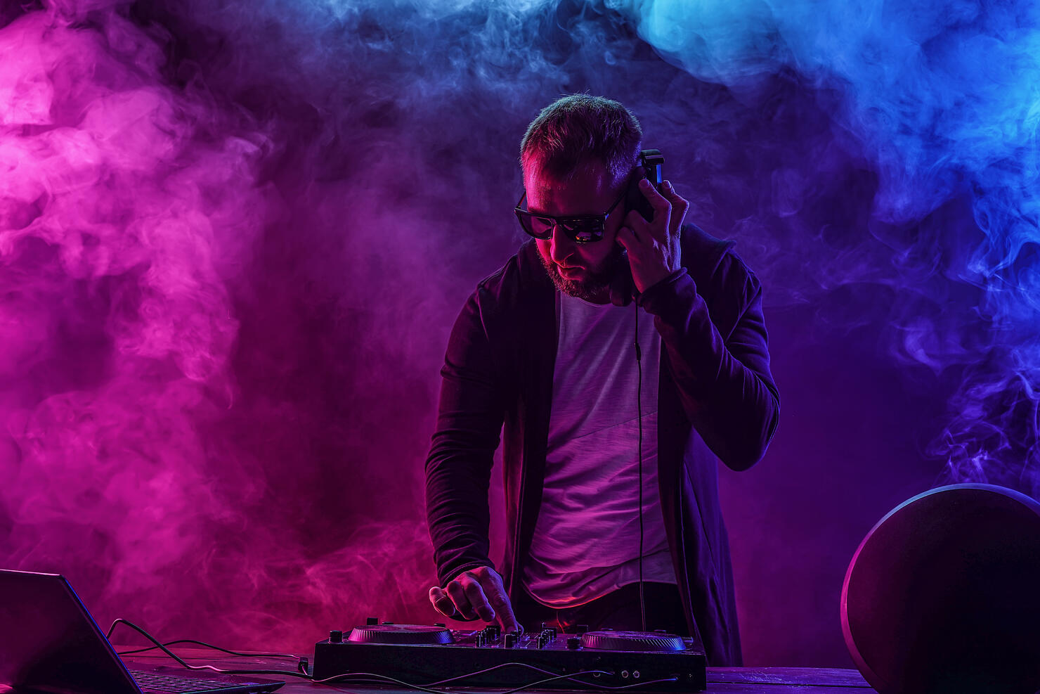 Trendy male dj posing against mixing console