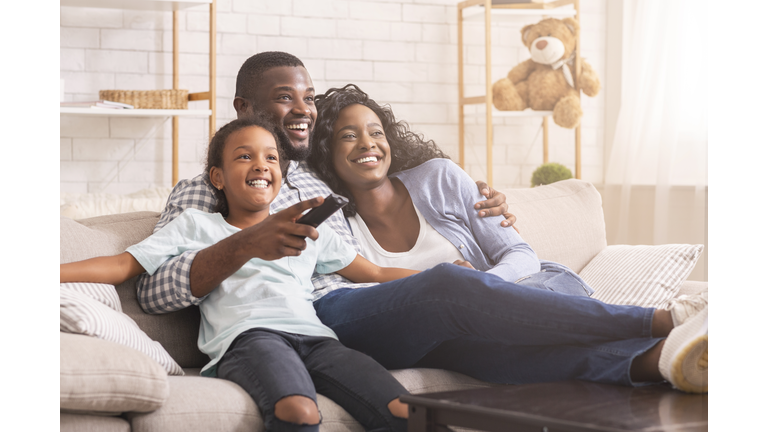 Happy black family relaxing and watching tv at home